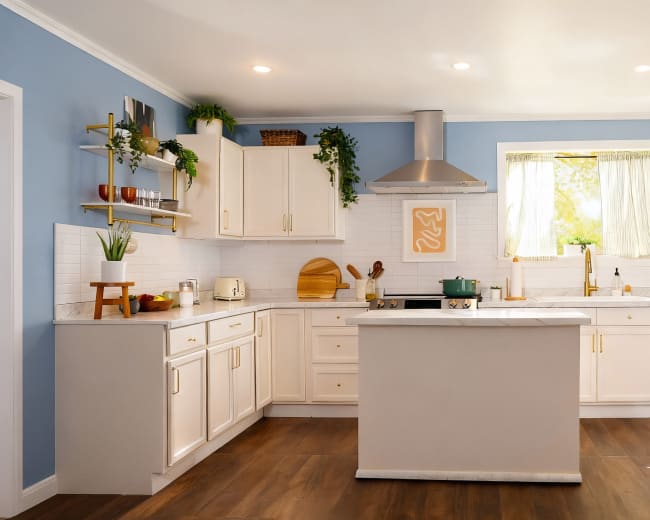 The image shows a modern kitchen with white cabinets, a central island, stainless steel appliances, and light blue walls.