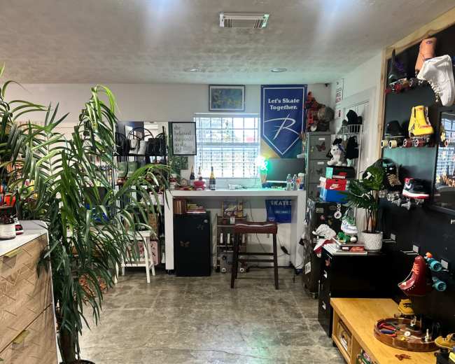 The image shows an organized indoor space with a variety of roller skates, decorations, and plants, creating a lively atmosphere.