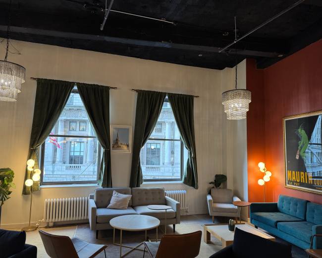 The scene shows a modern lounge area with large windows, green curtains, various seating options, and decorative lighting fixtures.