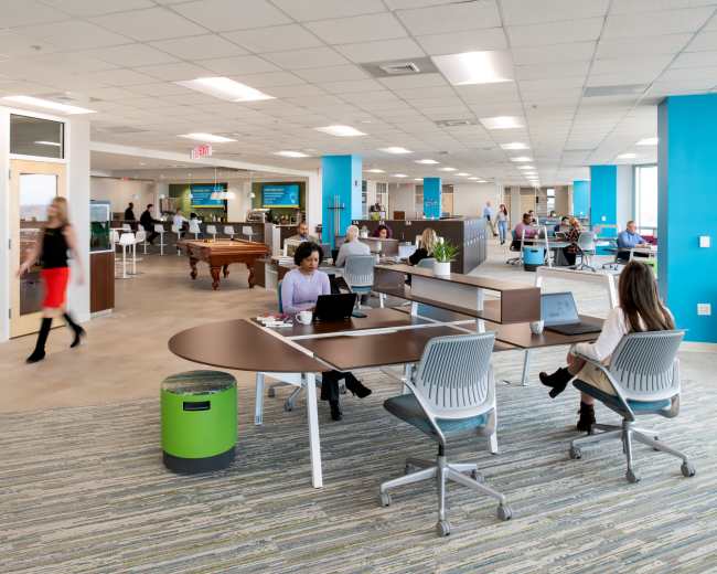 An open office space features workstations, a pool table, and areas for collaboration, with employees engaged in various tasks.