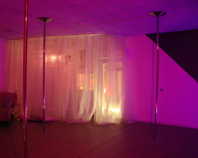 A dimly lit room with two metallic poles and sheer curtains, creating a cozy atmosphere.