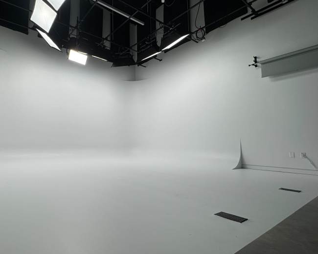 The image shows a spacious, well-lit studio with a white backdrop and soft corners.