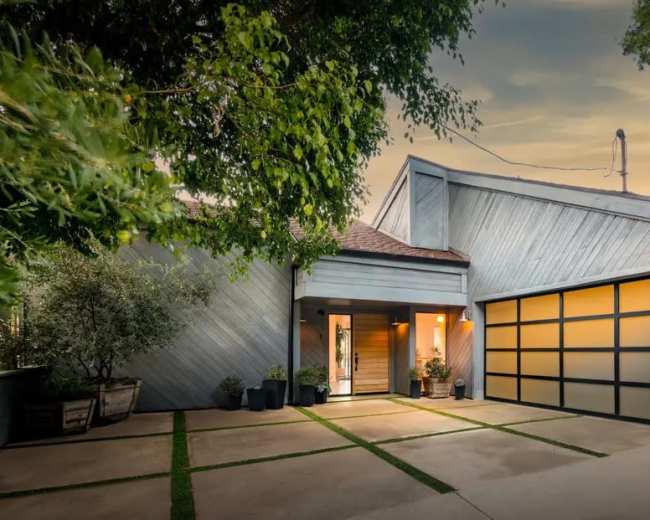 A modern single-story house features a gray exterior, a welcoming entrance, and a garage with glass door panels.