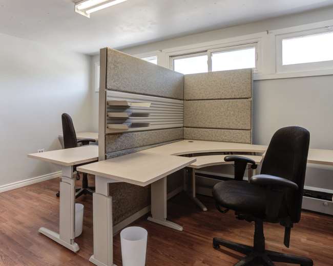 A small office space with two chairs and a corner desk separated by a panel.