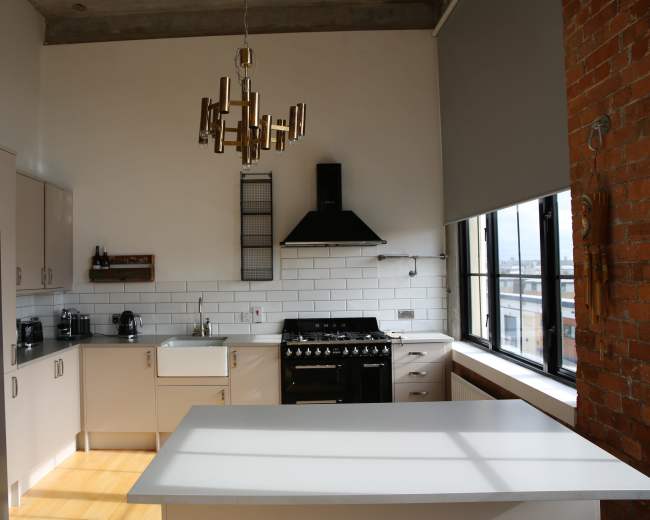 The kitchen features modern cabinetry, a large island, and a gas stove beneath a wall-mounted range hood.