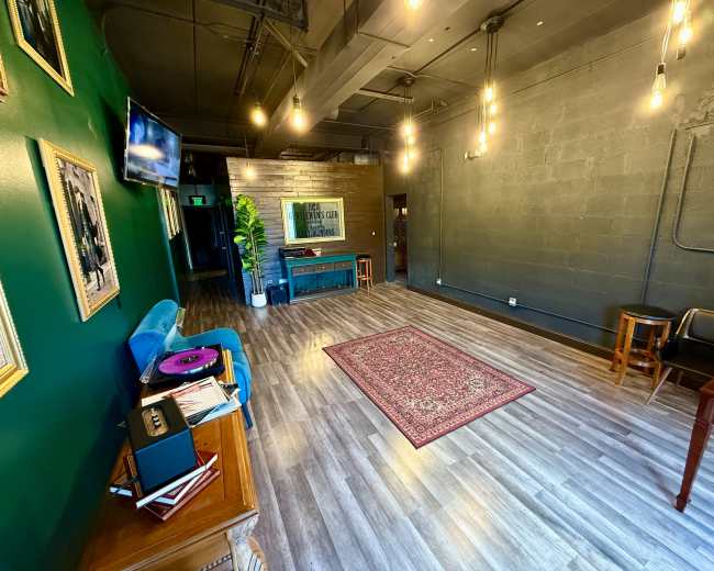 The interior of a modern room features a green accent wall, hardwood flooring, vintage decor, and pendant lighting.