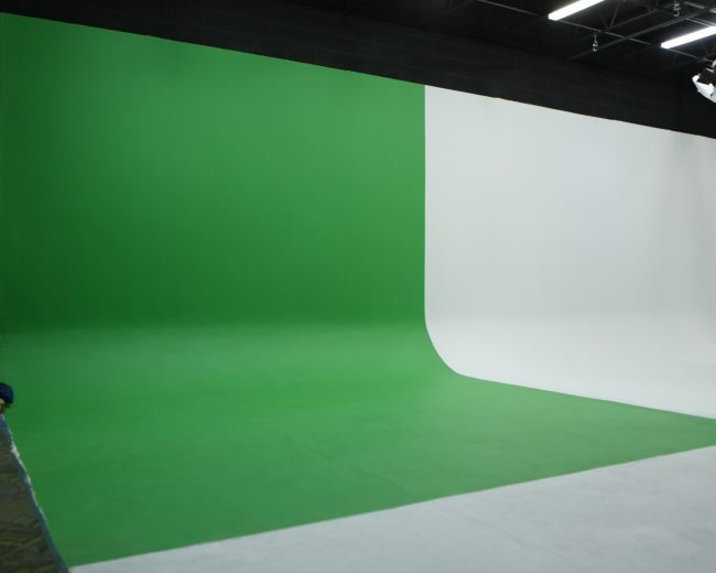 A studio features a green screen on one side and a white backdrop on the other.