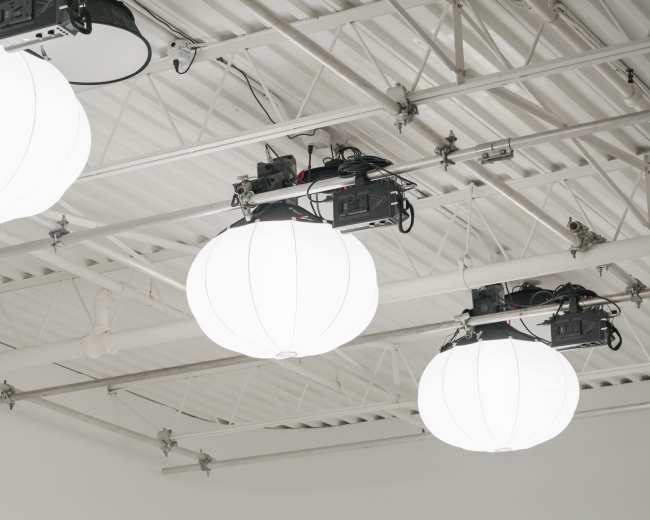 The image shows a ceiling with three large, spherical white light fixtures suspended from metal supports.