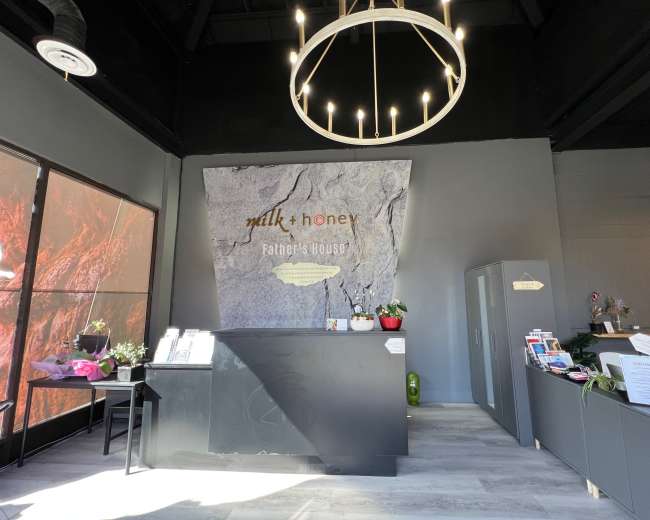 The interior of a reception area features a stone wall with a logo, a circular light fixture, and a black front desk.