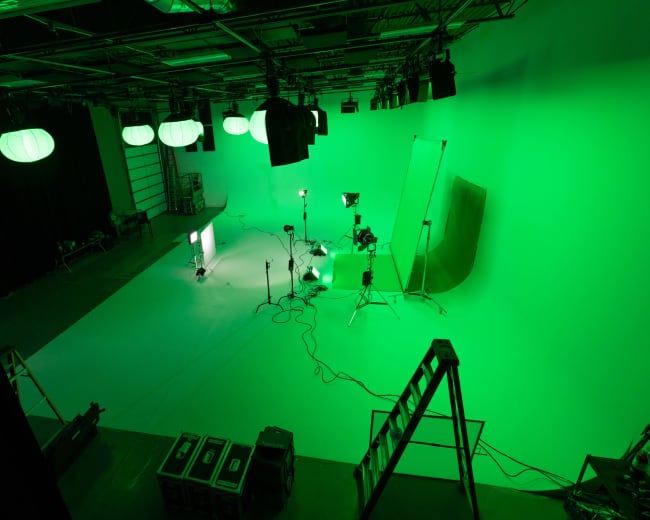 A green studio setup with lighting equipment and a blank backdrop.
