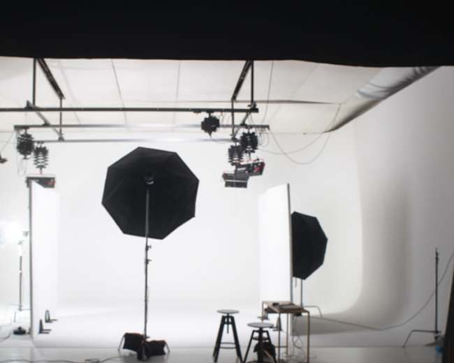 A photography studio is set up with softboxes, stands, and a seamless backdrop.