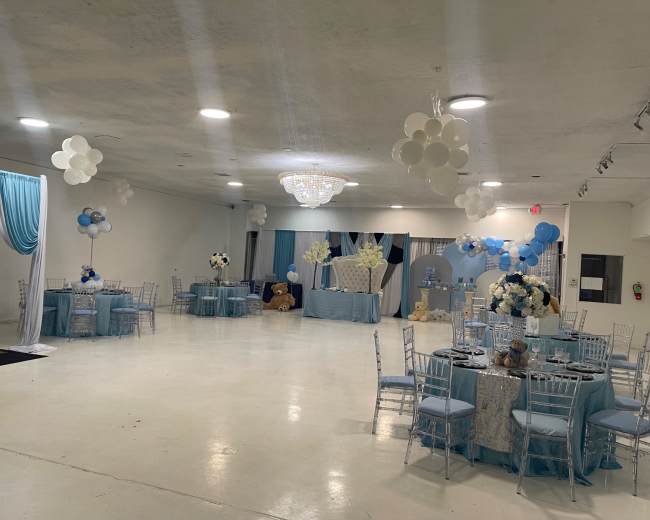 A reception hall decorated in blue and white with tables set for an event and various balloon decorations.