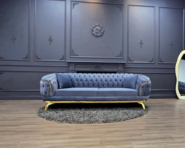 The image shows a luxurious sitting room featuring a dark wall, a velvet blue sofa with gold accents, a decorative silver mirror, and an ornate silver chair.