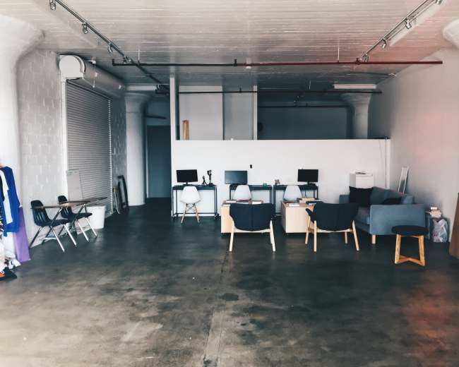 A spacious, minimally furnished room with office chairs and desks arranged along one side.