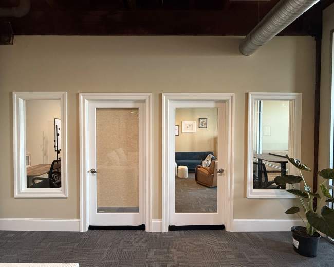 Three framed doorways are positioned in a row on a wall, leading into separate rooms, with one doorway featuring a sheer curtain.