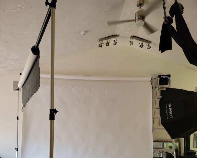 An empty photography studio with a white backdrop and a single stool positioned in front of it.