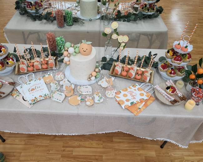 A dessert table adorned with a variety of treats, including a decorated cake, cupcakes, candies, and themed decorations, all arranged on a beige tablecloth.