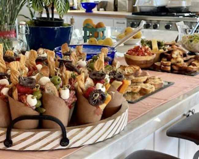 The image displays a buffet spread featuring various food items, including decorative cones filled with snacks, bowls of salad, and an assortment of pastries on a table.