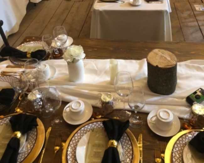 The image shows a banquet hall with long tables set for a formal dinner, adorned with white tablecloths, elegant place settings, and centerpieces.