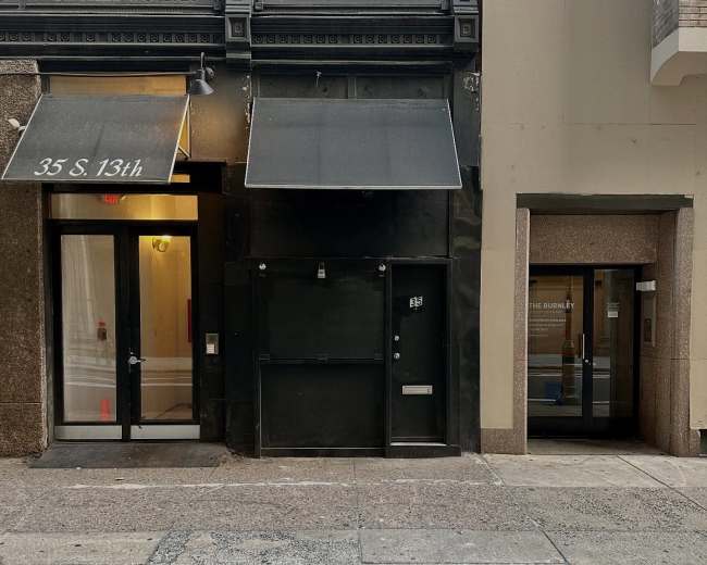 The image shows a street view of two adjacent buildings with distinct entrances, one featuring a black door and awning, and the other with a glass door labeled "THE BENJAMIN."