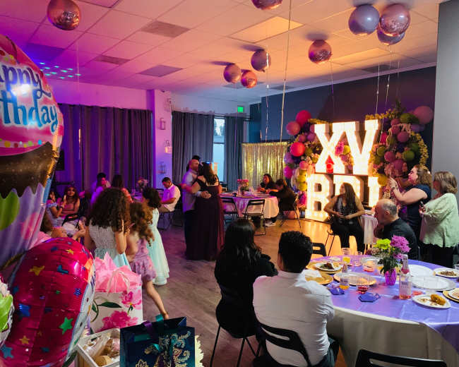 A celebration scene featuring a large "XV BD" marquee sign, with guests enjoying food and dancing at a birthday party.