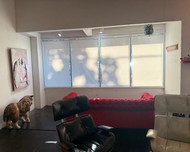 The image shows a room with a red couch, assorted chairs, a large cat statue, and a window covered by blinds.