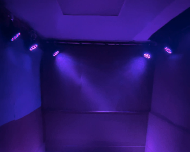 A dimly lit, empty room with purple lights illuminating the walls and floor.