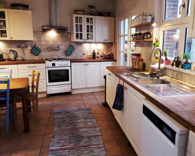 A bright kitchen features white cabinets, a wooden countertop, a stove, and a dining table with chairs.