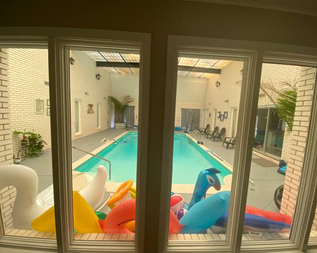 The image shows a view of an indoor swimming pool surrounded by inflatable toys and lounge chairs.