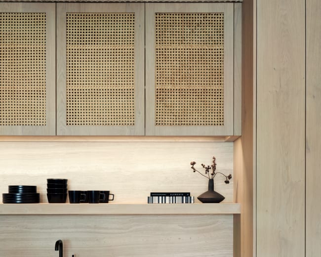 The image shows a modern kitchen featuring wooden cabinetry, open shelving with black dishware, and a sink with a black faucet.