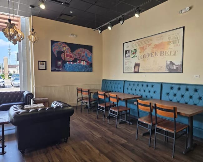 The image shows a coffee shop interior with tufted teal seating, wooden tables, and decorative wall art.