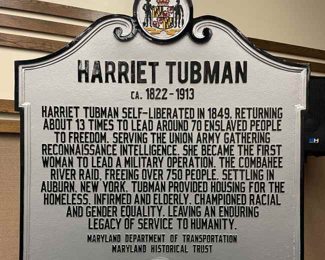 The image shows a historical marker for Harriet Tubman, detailing her contributions, including her work with the Union Army and her advocacy for housing and services for the homeless and elderly.