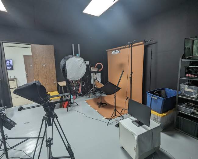A photography studio setup with a backdrop, lighting equipment, and various props organized on shelves.