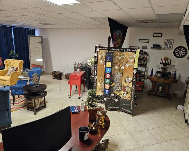 A spacious and colorful lounge area with various seating options, a decorative screen, and a bar setup in a well-lit room.