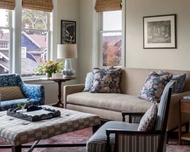 The living room features a sofa and chairs arranged around a coffee table, with large windows allowing natural light to illuminate the space.