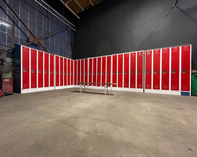 A row of red lockers against a black wall in a spacious, industrial setting.