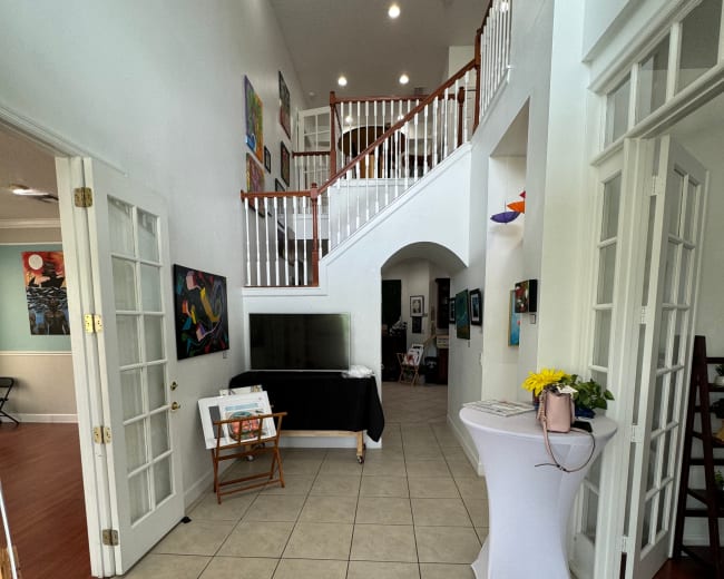 A spacious, well-lit foyer with a central staircase and art displays on the walls.