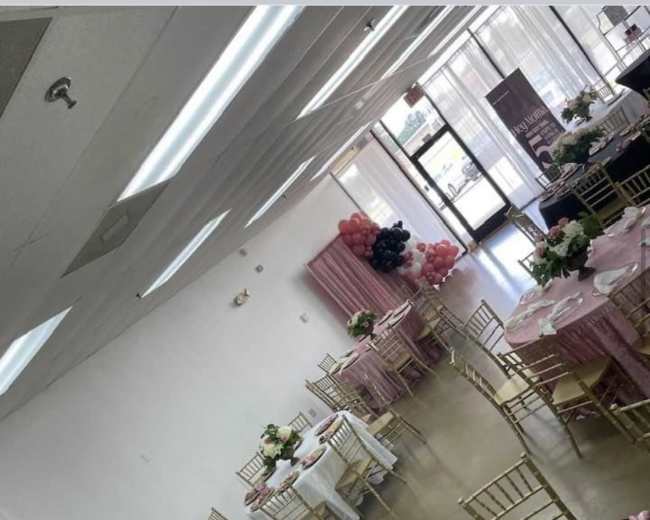 A banquet hall set up with various tables decorated with floral centerpieces and table coverings in different colors.