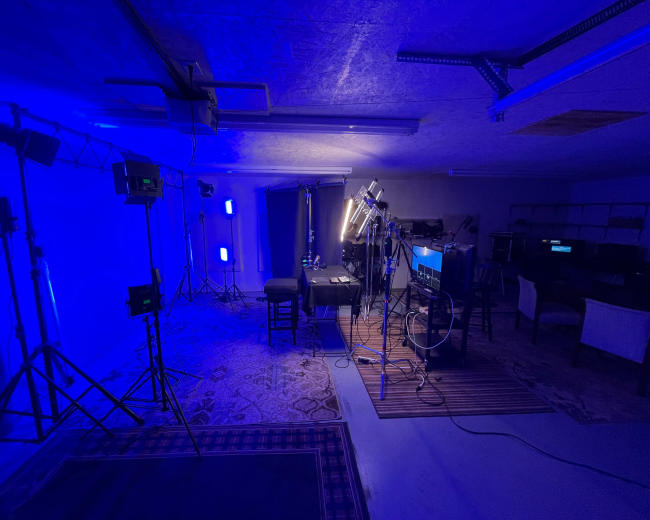 A dimly lit studio setup with various lighting equipment, a table in the center, and a backdrop.