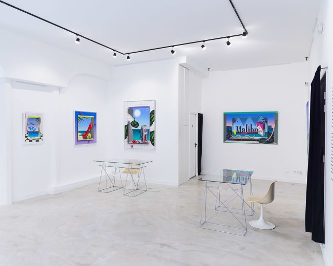 The image shows a modern art gallery with white walls, featuring colorful artwork and minimalistic furniture.