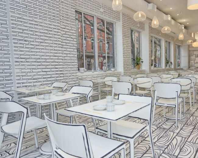 The image shows a modern restaurant with white furniture and a hand-drawn black and white design on the walls and floor.