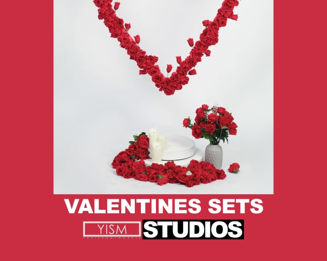 The image features a heart-shaped arrangement of red roses on a white background, accompanied by a bouquet of roses and candles on the floor.