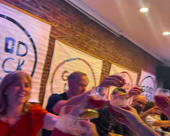 A group of people is raising their glasses in a toast at a celebratory gathering around a table.