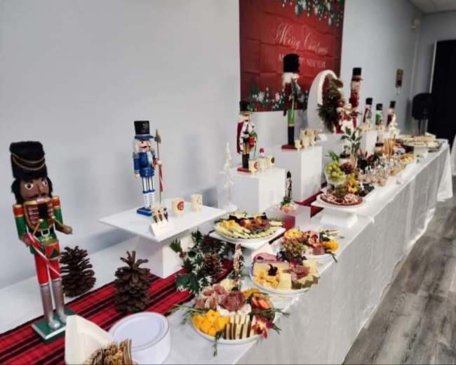 A festive buffet table adorned with various decorated platters of food, accompanied by nutcracker figurines and holiday decor.