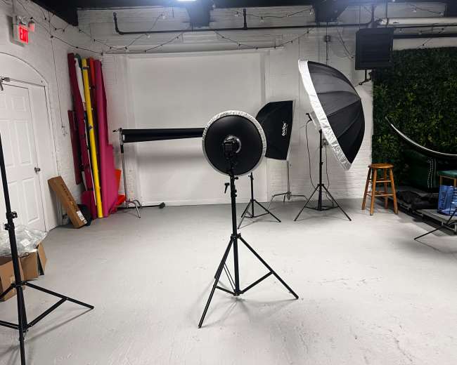 A photography studio setup with various lighting equipment and backdrops arranged in the space.