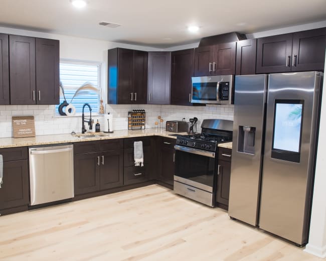 The kitchen features dark wooden cabinets, stainless steel appliances, and a light-colored countertop with a tiled backsplash.