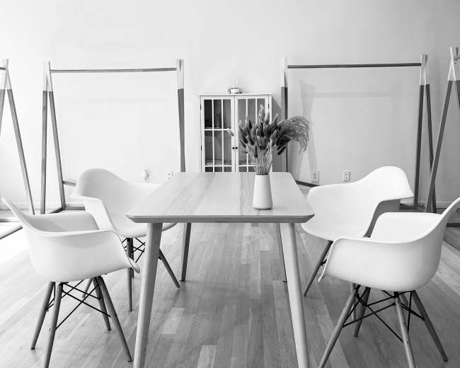A light-filled room features a wooden table surrounded by four white chairs.