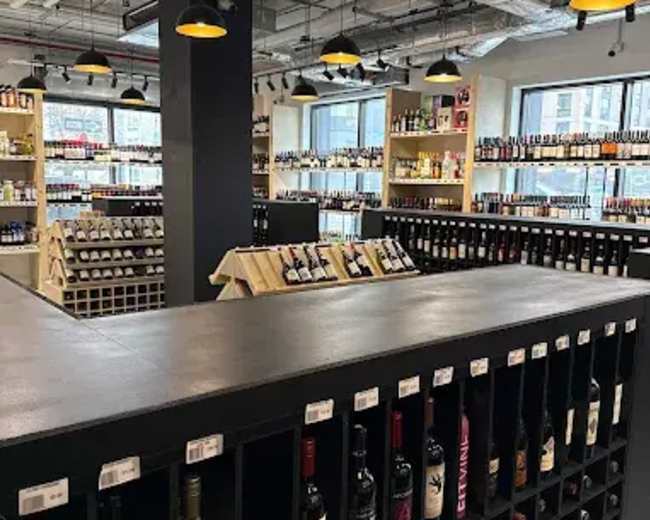The image shows an interior of a wine shop featuring shelves stocked with various wine bottles and a central display area.