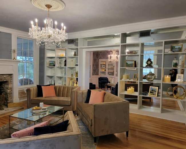 A elegantly designed living room featuring two plush sofas, a glass coffee table, and a bookshelf filled with decorative items and candles.