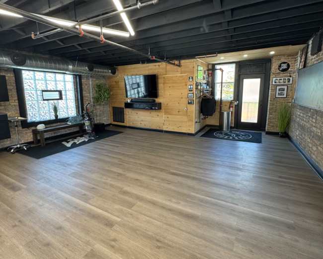 The image shows a spacious, modern interior with wooden paneling, a large TV on the wall, and a clean, minimalistic design.